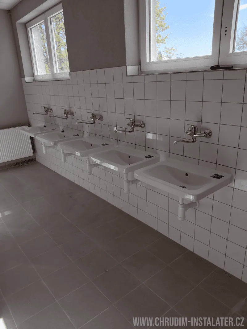 Řada namontovaných umyvadel s nástěnnými vodovodními bateriemi
